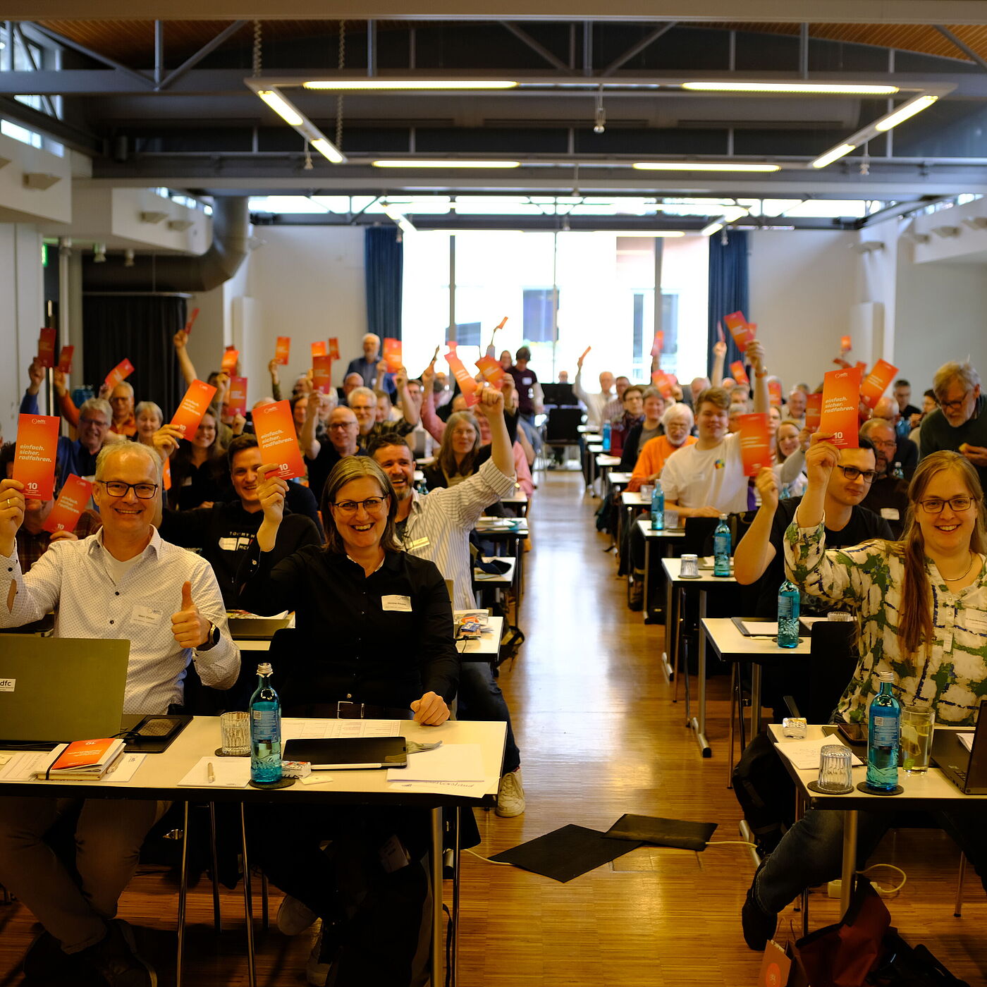 2026_04_18_Landesversammlung_Muenster_ADFC-NRW Viele Delegierten halten einen Flyer hoch