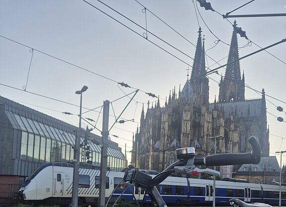 Nahverkehrszug am Hauptbahnhof in Köln. Fahrrad auf Bahnsteig. Dom im Hintergrund.