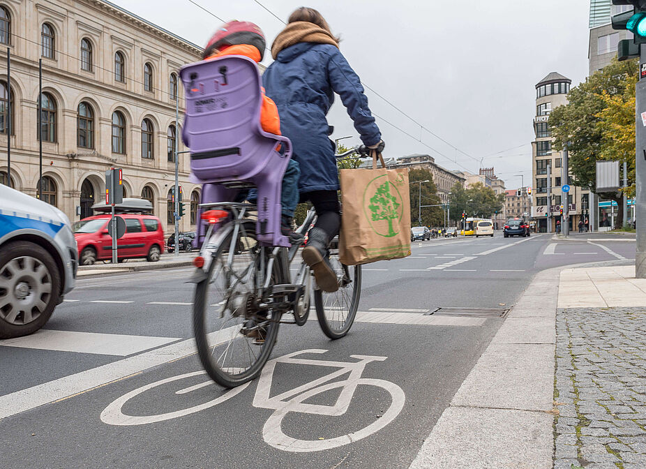 Fahrradfahren in der Stadt Frau mit Kind auf dem Rad in der Stadt unterwegs